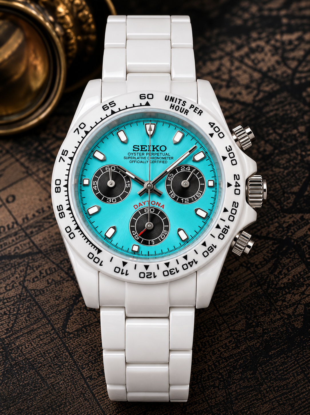 A Seiko Daytona watch with a white ceramic case and strap, featuring a bright turquoise blue dial with black subdials and a black tachymeter bezel, set against a dark textured background.